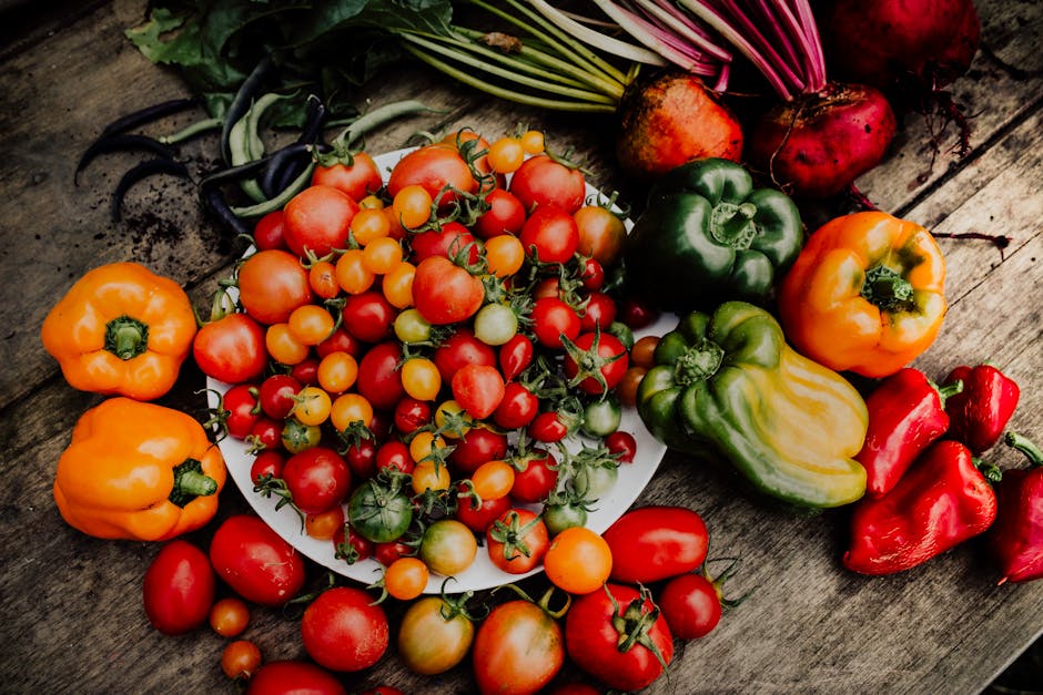 A bountiful harvest of various fresh vegetables like tomatoes, cucumbers, and peppers, arranged on a wooden table.