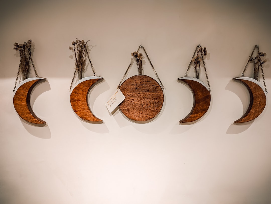 A collection of various laser cut wood wall hangings with intricate geometric and floral patterns displayed on a light-colored wall.