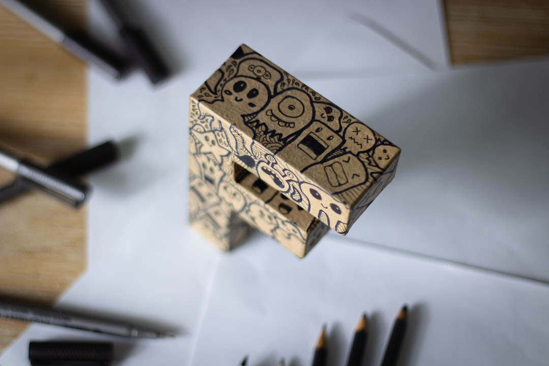 A hand sketching a custom laser cut wood sign design on paper with a pencil, showing initial layout ideas.